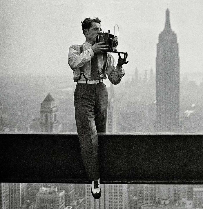 "Fotograf Charles Ebbets pořizující slavnou fotografii dělníků během polední přestávky v nedokončeném mrakodrapu v New Yorku, 1932"