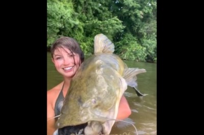 Dziewczyna własnymi rękoma wyciąga z wody ogromnego suma 